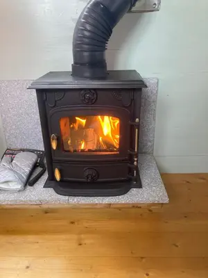 a black stove with a fire in a room at Shepherds hut on alpaca farm in Blaenau-Ffestiniog