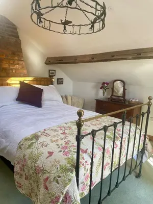 a bedroom with a bed and a chandelier at The Old Smithy, beautifully restored cottage in Carreghofa, near Llanymynech in Llanymynech