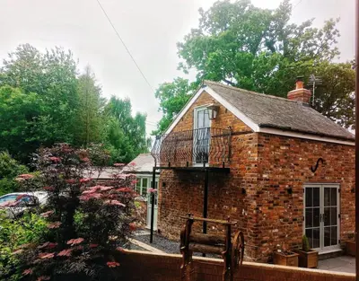 a brick house with a balcony on top of it at The Old Smithy, beautifully restored cottage in Carreghofa, near Llanymynech in Llanymynech