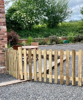 a wooden fence with a table in a garden at The Old Smithy, beautifully restored cottage in Carreghofa, near Llanymynech in Llanymynech