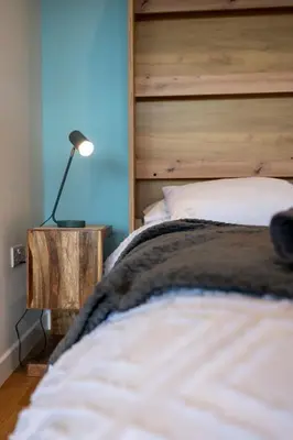 a bedroom with a bed with a wooden headboard and a lamp at Bermo Cwtch in Barmouth
