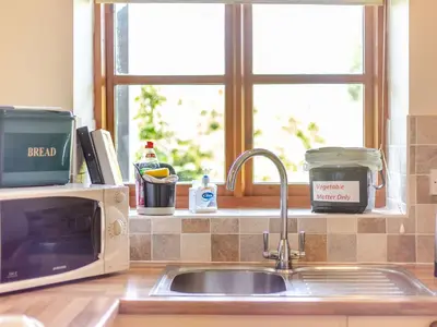 a kitchen counter with a sink and a microwave at Swallow's Nest in Craven Arms