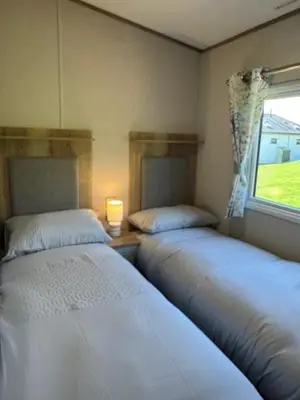 two beds sitting in a room with a window at The Harlech, Penygraig Caravan Park in Borth