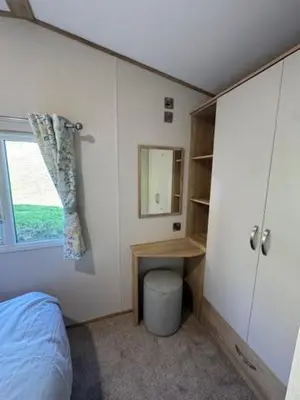 a bedroom with a bed and a desk and a window at The Harlech, Penygraig Caravan Park in Borth
