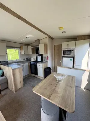 a kitchen with a wooden table in a room at The Harlech, Penygraig Caravan Park in Borth