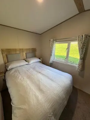 a bedroom with a large bed with a window at The Harlech, Penygraig Caravan Park in Borth