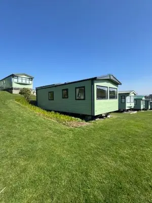 a tiny house sitting on top of a lush green field at The Harlech, Penygraig Caravan Park in Borth