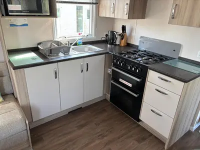 a small kitchen with a stove and a sink at Coastal Serenity Escape Clarach Bay Sea Viev Modern 2019 model No Pets in Aberystwyth