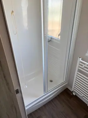 a glass shower in a room with a window at Coastal Serenity Escape Clarach Bay Sea Viev Modern 2019 model No Pets in Aberystwyth