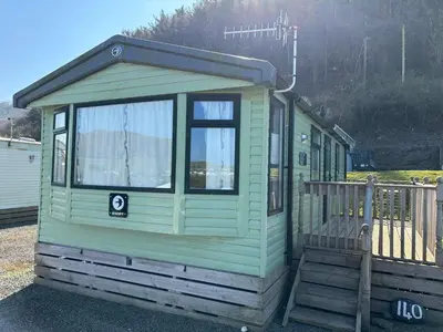 a green tiny house sitting on the ground at Coastal Serenity Escape Clarach Bay Sea Viev Modern 2019 model No Pets in Aberystwyth