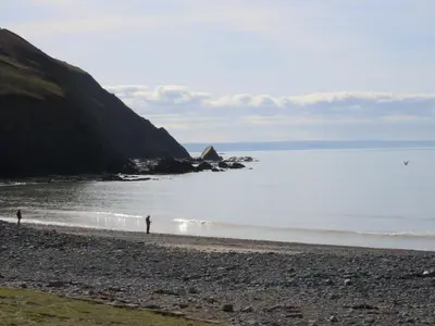 two people standing on a beach near the water at Coastal Serenity Escape Clarach Bay Sea Viev Modern 2019 model No Pets in Aberystwyth