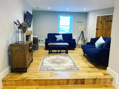 a living room with two blue couches and a rug at Gwel y Don 12 Tabenacle Street in Aberaeron