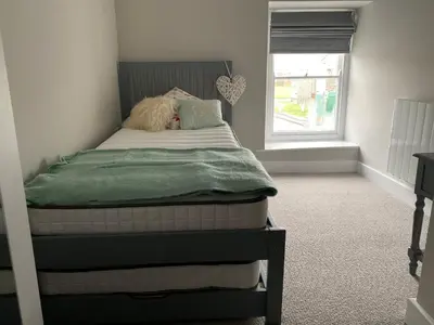 a bedroom with a bed with a green blanket and a window at Gwel y Don 12 Tabenacle Street in Aberaeron