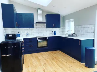 a kitchen with blue cabinets and wooden floors at Gwel y Don 12 Tabenacle Street in Aberaeron