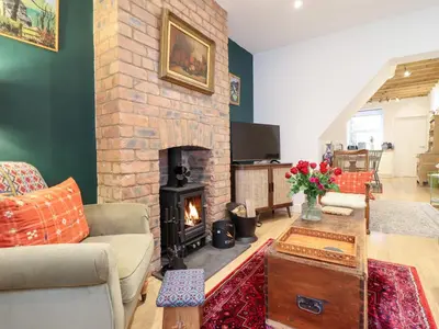 a living room with a brick fireplace and a couch at Derwen House in Llangollen