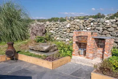 a garden with a brick fireplace and a stone wall at Glanaber in Dyffryn
