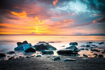 a sunset on a beach with rocks in the water at Glanaber in Dyffryn