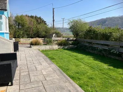 a backyard with a lawn and a fence at Blue Lodge - by the sea, sauna, BBQ, private garden and parking in Aberystwyth