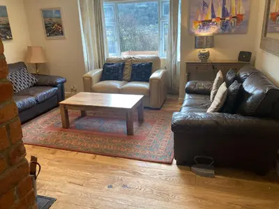 a living room with leather couches and a coffee table at Blue Lodge - by the sea, sauna, BBQ, private garden and parking in Aberystwyth