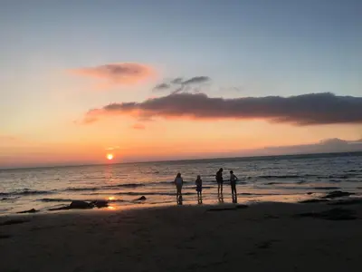 three people standing on the beach at sunset at POD4 Family Glamping with seaview & Wi-Fi in Llwyngwril