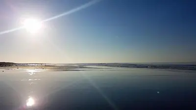 a beach with the sun shining on the sand at POD4 Family Glamping with seaview & Wi-Fi in Llwyngwril