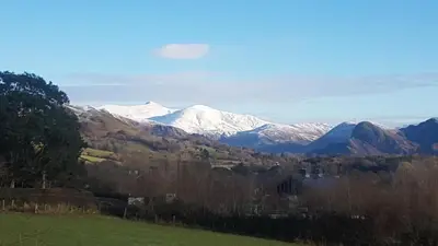 a view of a snow covered mountain in a field at POD4 Family Glamping with seaview & Wi-Fi in Llwyngwril