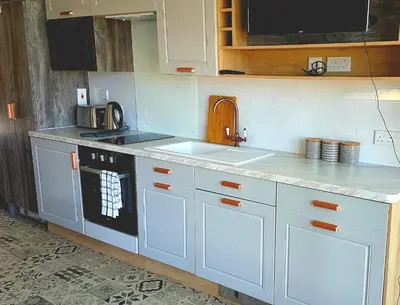 a kitchen with white cabinets and a stove top oven at POD4 Family Glamping with seaview & Wi-Fi in Llwyngwril