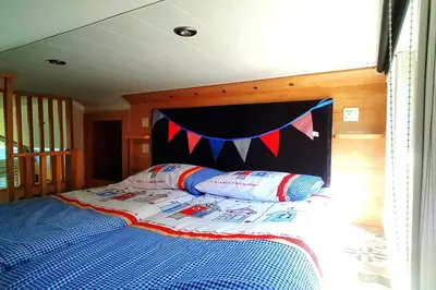 a bed with a blue comforter with a banner above it at POD6 Family Glamping with seaview & Wi-Fi in Llwyngwril