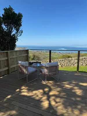 two chairs sitting on a deck looking at the ocean at coastal view shepherds hut with hot tub in Llanfair