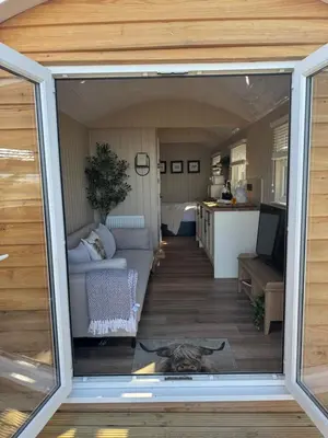 a view of a living room and kitchen from a window at coastal view shepherds hut with hot tub in Llanfair