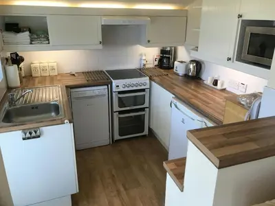 a small kitchen with white appliances and wooden floors at Llaethdy Rachel Lampeter in Aberaeron