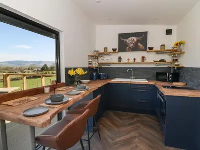a kitchen with a wooden table and a large window at Llety Cariad in Llandrindod Wells