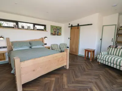 a bedroom with a wooden bed and a couch at Llety Cariad in Llandrindod Wells