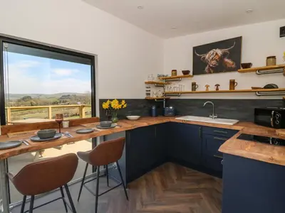 a kitchen with blue cabinets and a large window at Llety Cariad in Llandrindod Wells