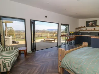 a bedroom with a bed and a kitchen with a balcony at Bryn Hafod in Llandrindod Wells
