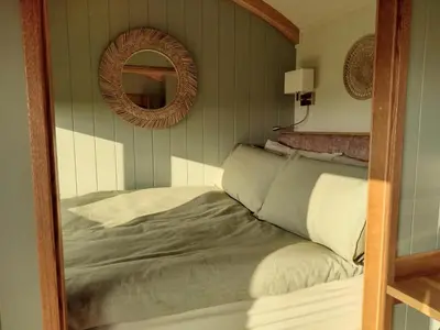 a mirror reflection of a bed in a bedroom at Fir Tree Shepherd's Hut in Llanon