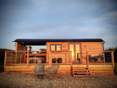 a tiny house with two chairs and a porch at Fir Tree Shepherd's Hut in Llanon