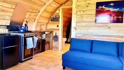 a living room with a blue couch and a stove at The Viking Lodge with Sauna in Ystrad-Meurig