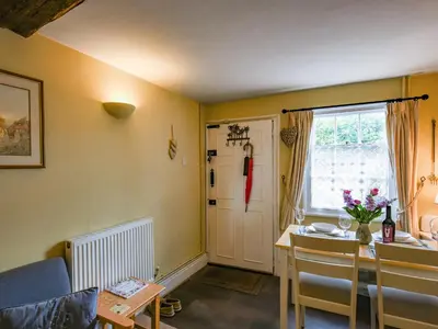 a living room with a table and a dining room at Flo's Cottage in Kington