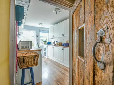 a kitchen with a door leading to a kitchen with white cabinets at Flo's Cottage in Kington