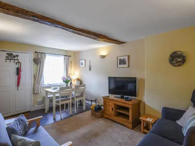 a living room with a couch and a tv and a table at Flo's Cottage in Kington