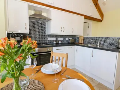 a kitchen with white cabinets and a wooden table at Cwtch in Ystrad Meurig
