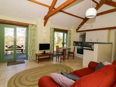 a living room with a red couch and a kitchen at Cwtch in Ystrad Meurig