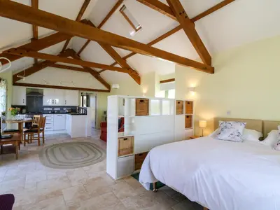 a bedroom with a large bed and a kitchen at Cwtch in Ystrad Meurig