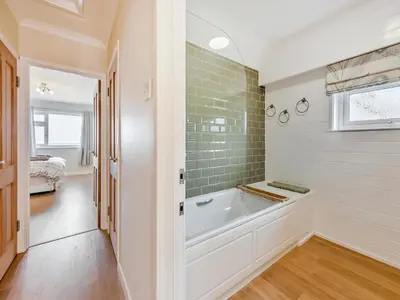 a white bathroom with a tub and a window at Yr Encil in New Quay