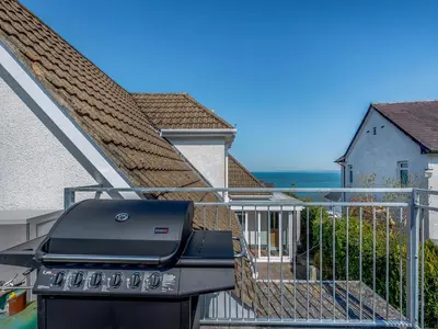 a bbq grill on the balcony of a house at Yr Encil in New Quay