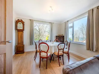 a dining room with a table and chairs and a grandfather clock at Yr Encil in New Quay