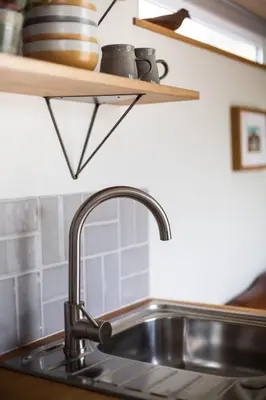 a kitchen counter with a sink and a shelf at Beautiful Cabin Near Hay-on-Wye in Peterchurch