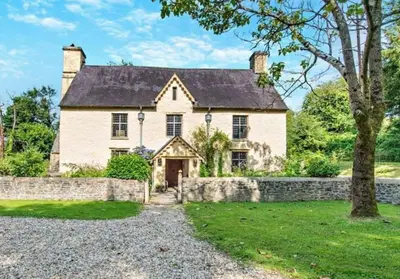 a large white house with a stone wall at Beautiful Brecon Beacon House in Llandovery