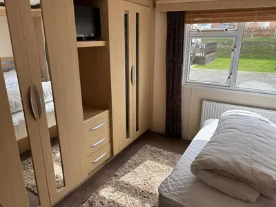 a small bedroom with a bed and a window at The Beach Hideaway Pet Friendly 2 Bedroom Static Caravan Clarach Bay in Aberystwyth